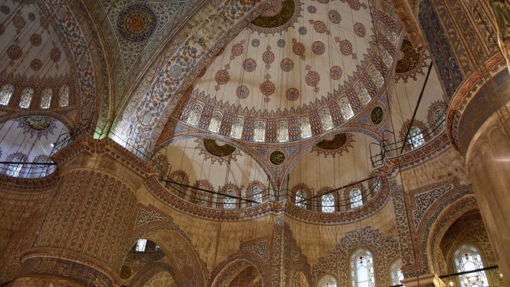 A view upwards towards the domes of a mosque, taking in all the intricate artistic details.