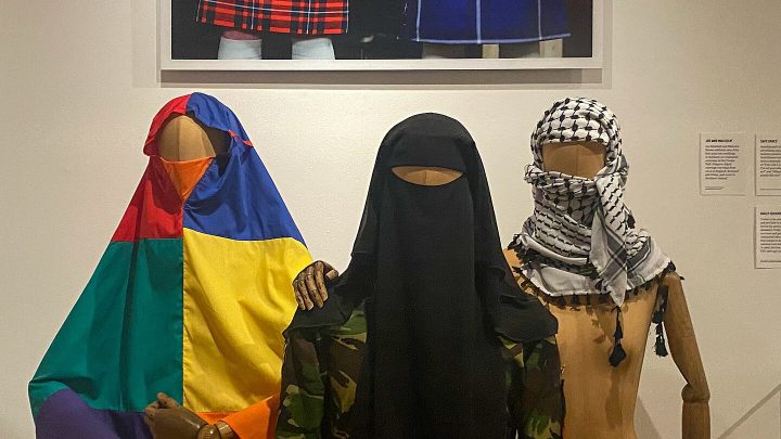 A rainbow khijmar is displayed alongside a camouflage shalwar kameez and a Palestinian Keffiyeh.